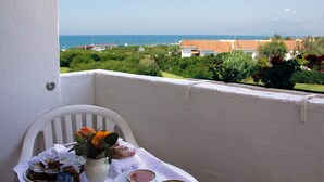 A balcony with a table set for two, overlooking a coastal view with houses and greenery. - Hotel Della Baia (Cellole)