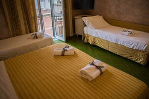 A hotel room with two beds, a small table, and a TV on the wall.