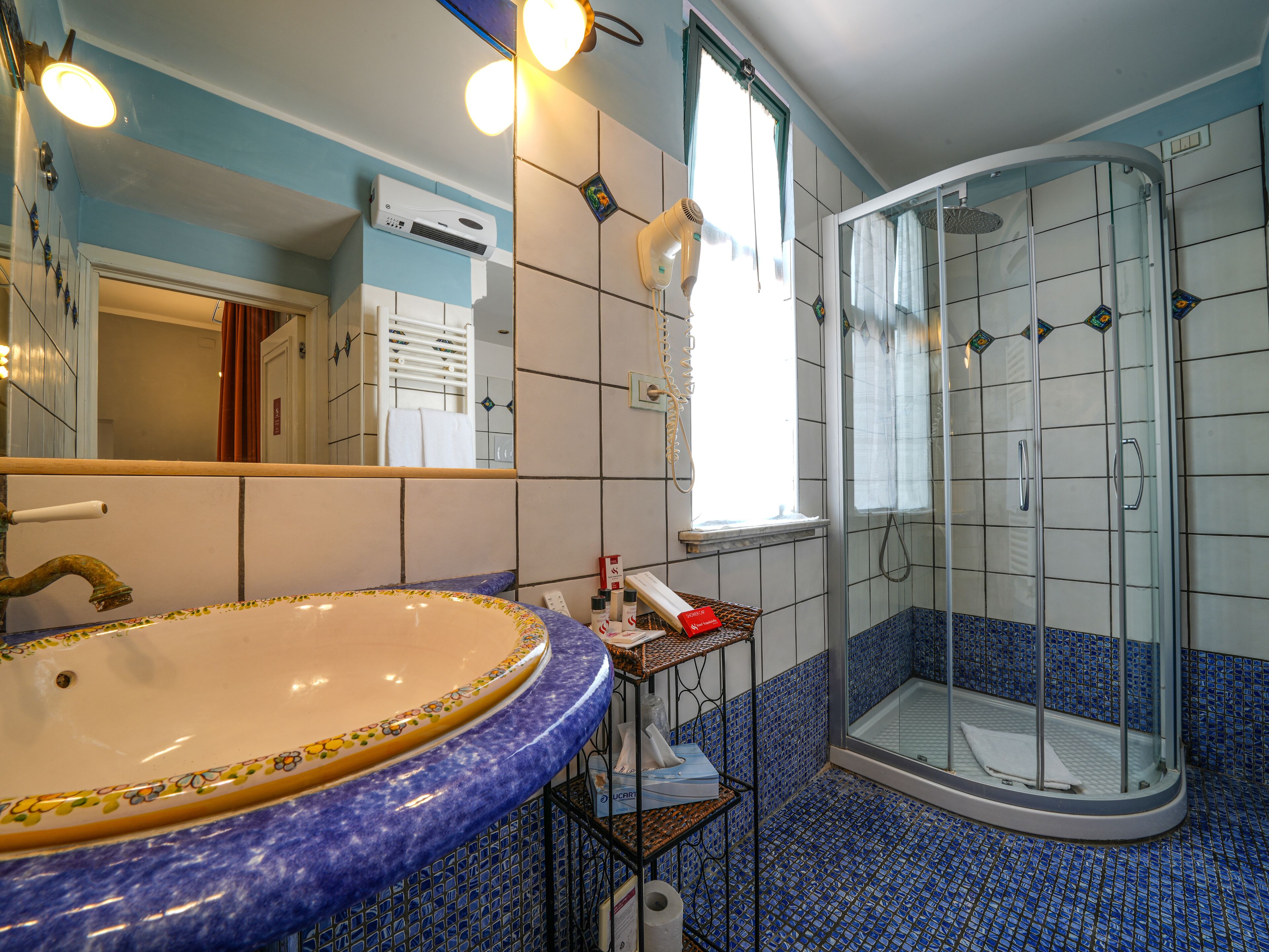 A bathroom with a large sink, a shower, and a mirror.