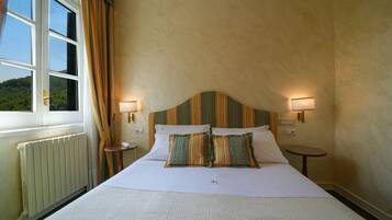 Habitación de hotel con una cama grande, dos mesitas de noche, una ventana con cortinas y vistas al exterior.