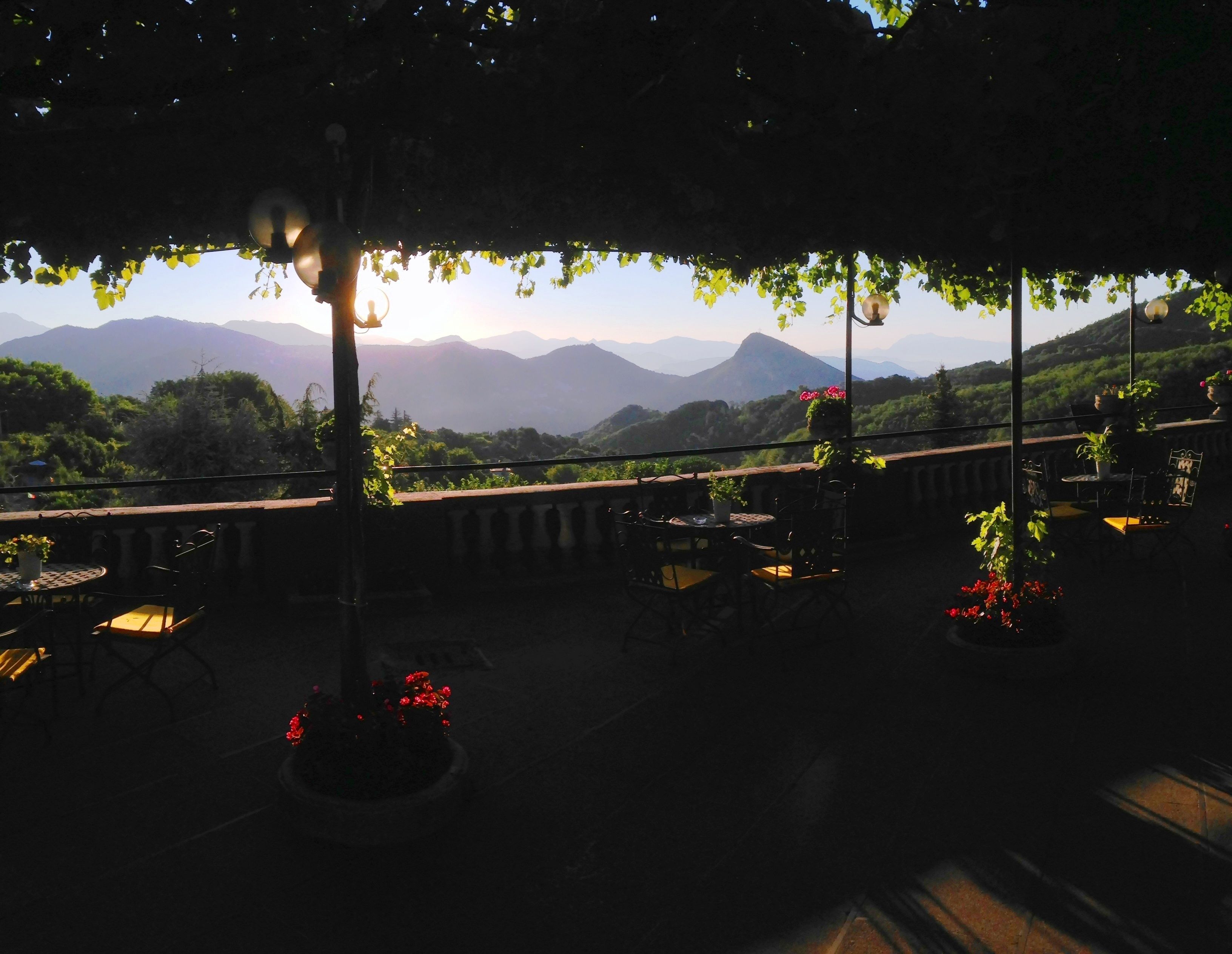 A terrace with tables and chairs, overlooking a mountainous landscape.
