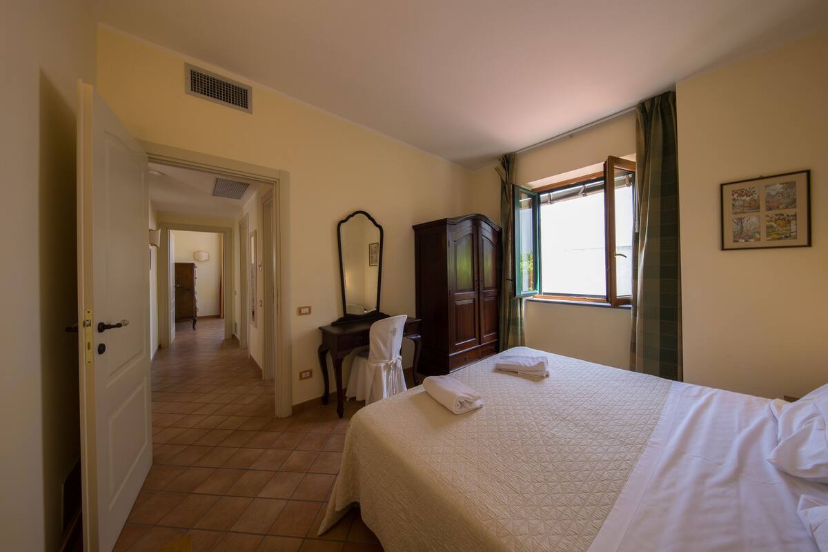 A hotel room with a bed, a desk, a chair, a wardrobe, and a window with curtains.