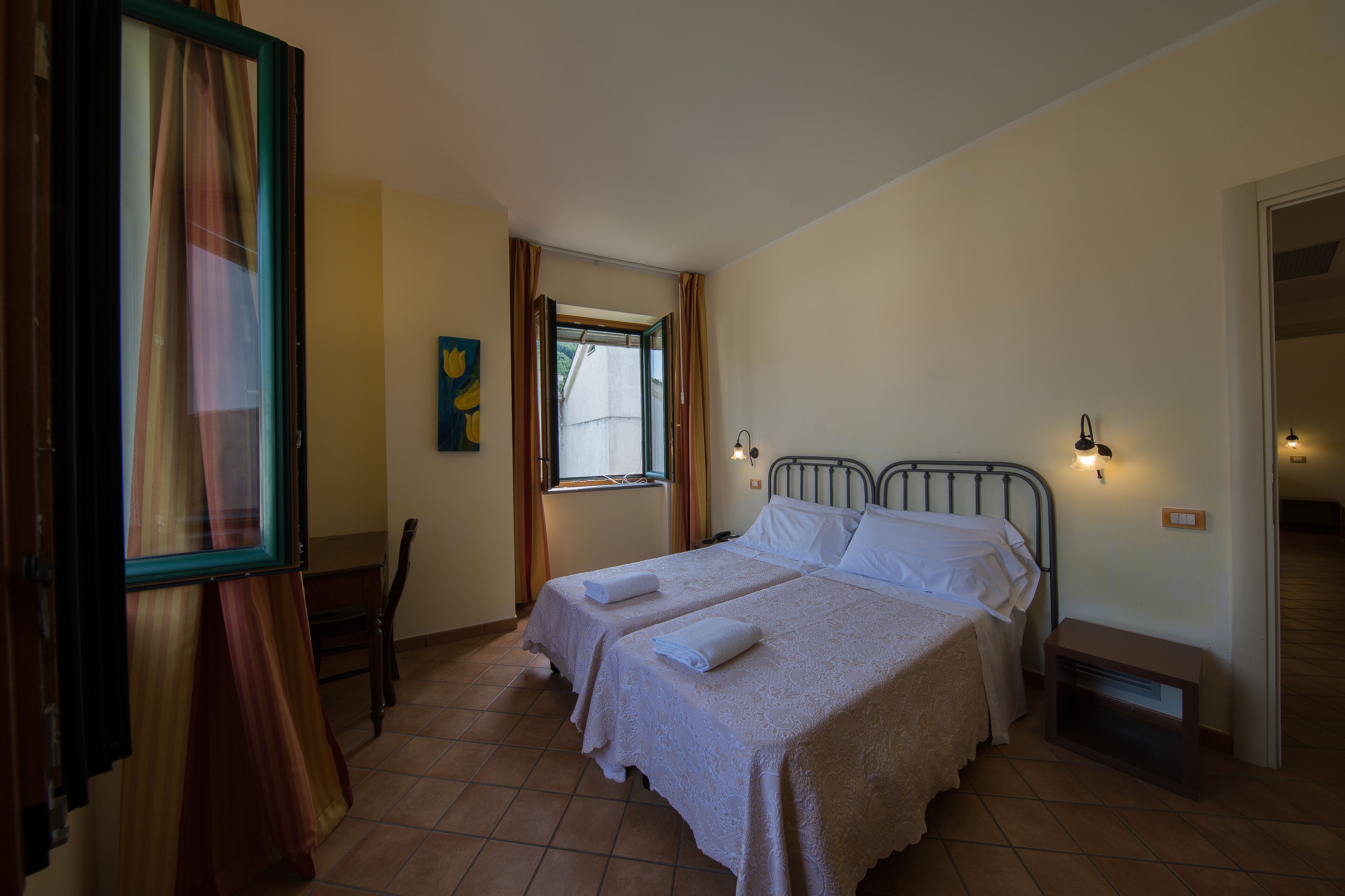 A bedroom with two beds, a window, and a door.