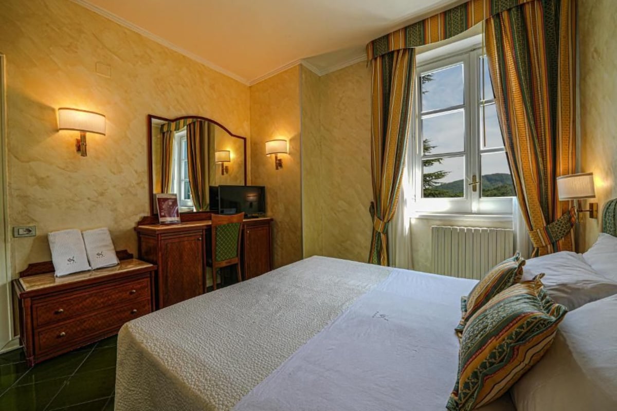 Hotelkamer met een bed, bureau, stoel, spiegel en twee wandlampen.