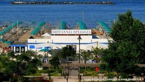 Un hotel frente al mar llamado "Britannia Spiaggia", con vista al mar y un muelle al fondo.