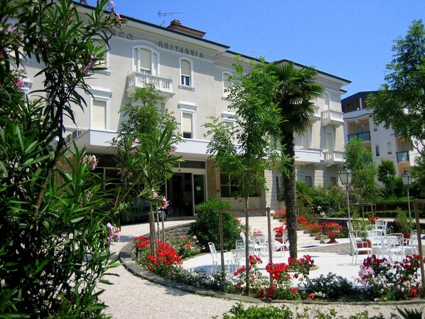 A hotel with a garden courtyard, outdoor seating, and a classic architectural style.