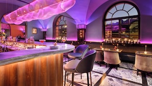 A bar area with a wooden bar counter, bar stools, and a large hanging light fixture. - Hotel Balestri (Florence)