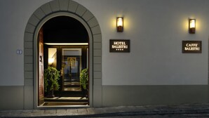 A hotel entrance with an arched doorway, illuminated signs reading "HOTEL BALESTRI" and "CAFFE' BALESTRI", and a number "7" on the wall. - Hotel Balestri (Florence)