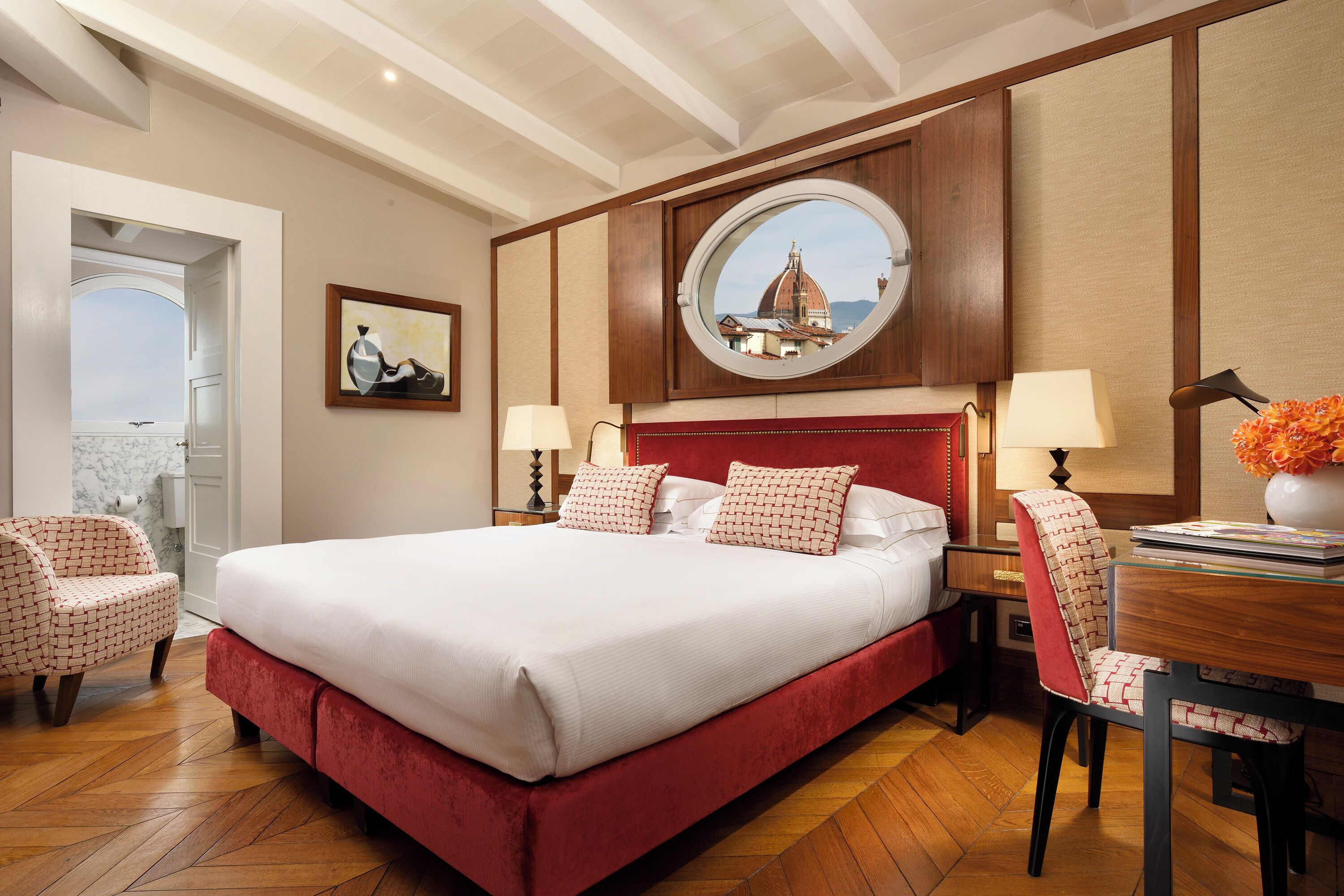 Habitación de hotel con una cama grande, un espejo redondo, una mesa de comedor y una silla.
