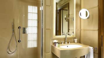 A bathroom with a glass-enclosed shower, a sink with a mirror, and a towel rack.