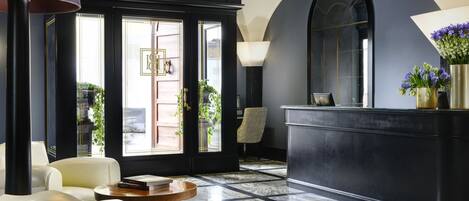 A lobby with a reception desk, seating area, and large windows with views of the outside.