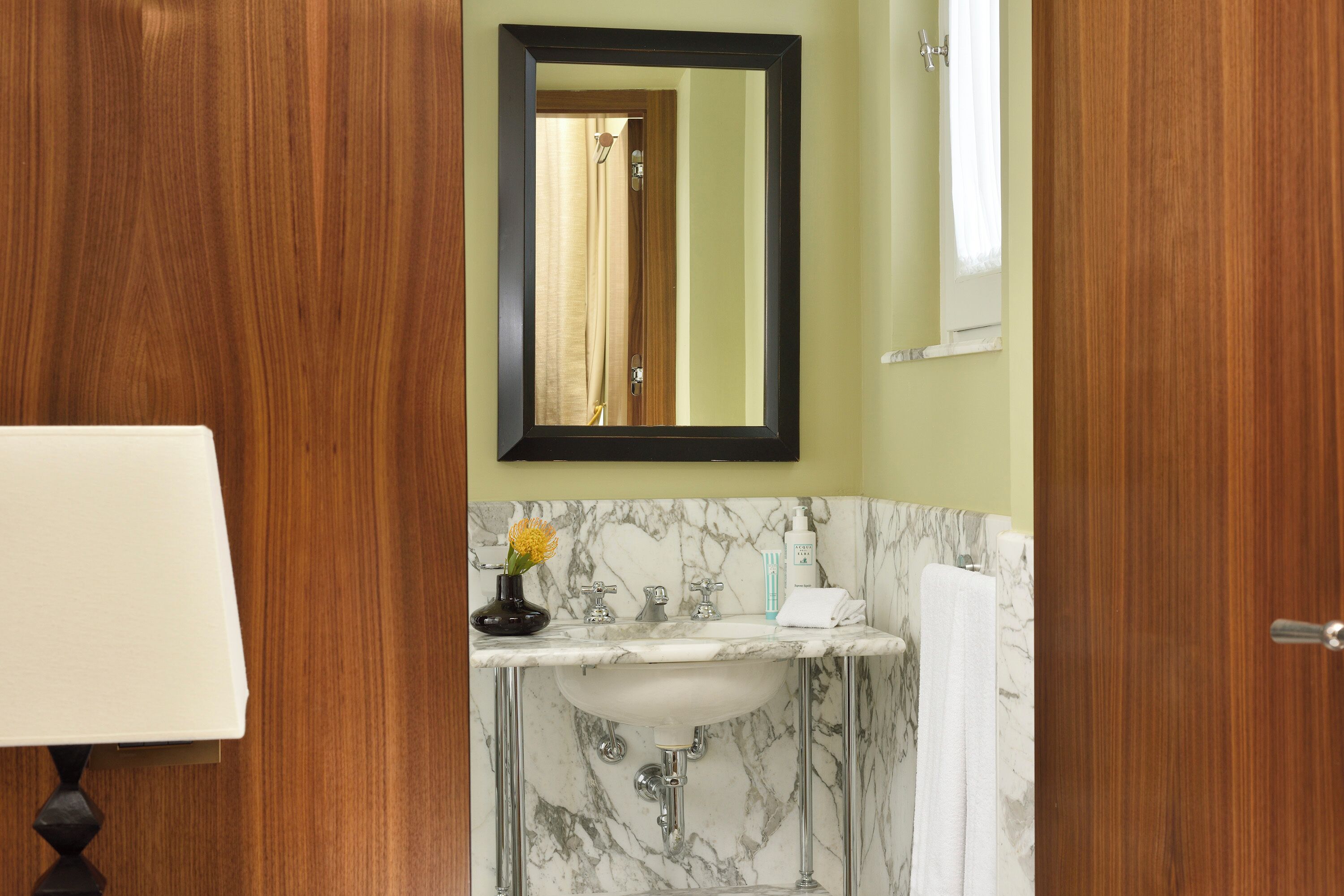 A bathroom with a marble sink, a mirror, and a wooden door.