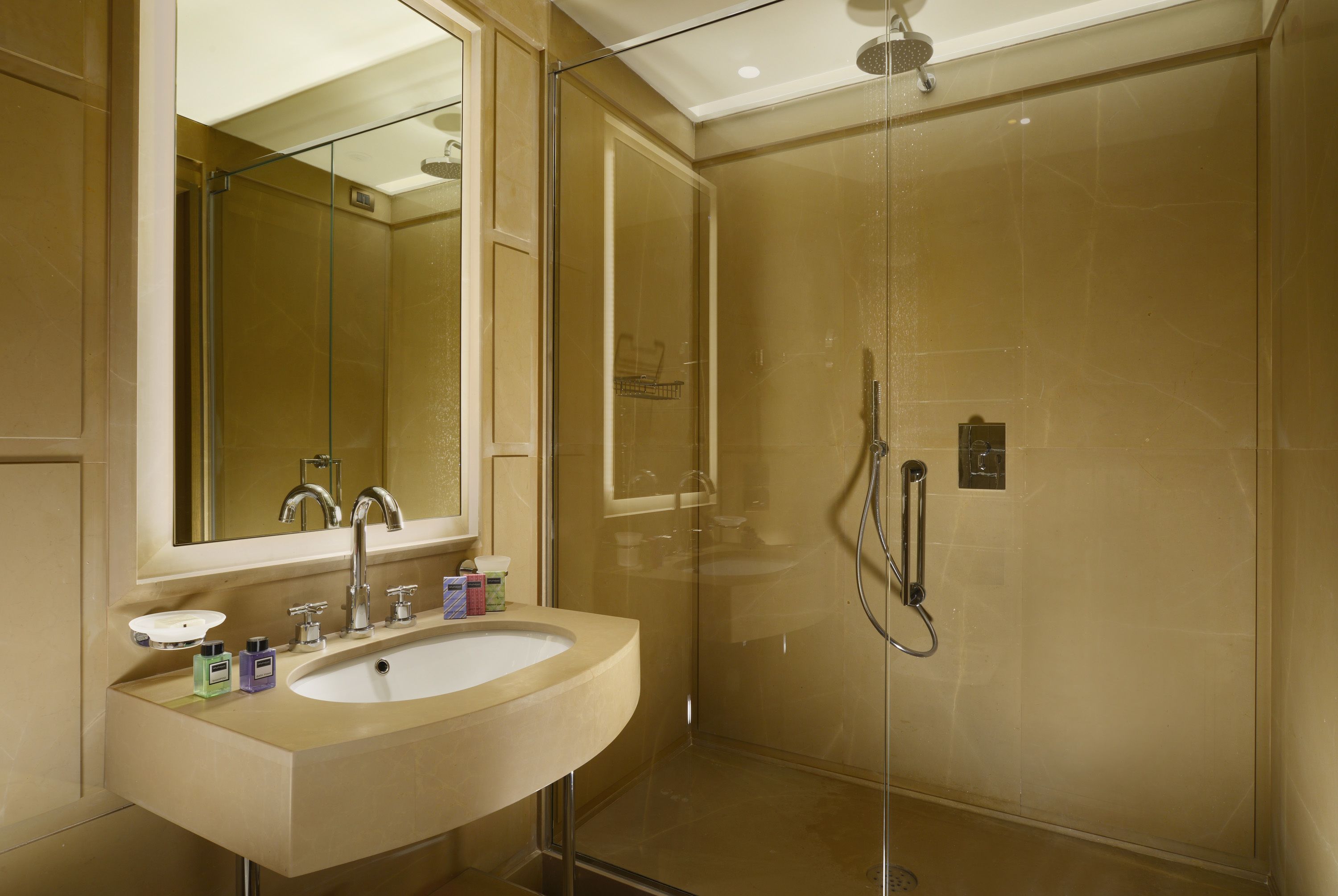 A bathroom with a beige sink, a mirror, and a glass-enclosed shower area.