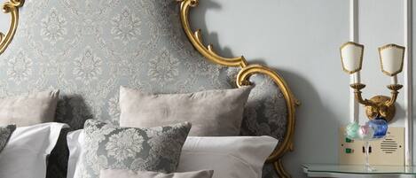 Un dormitorio con cama que presenta un cabecero dorado ornamentado, una colcha estampada y varias almohadas.