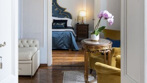 Een slaapkamer met een bed, nachtkastje, lamp, stoel en vloerkleed.