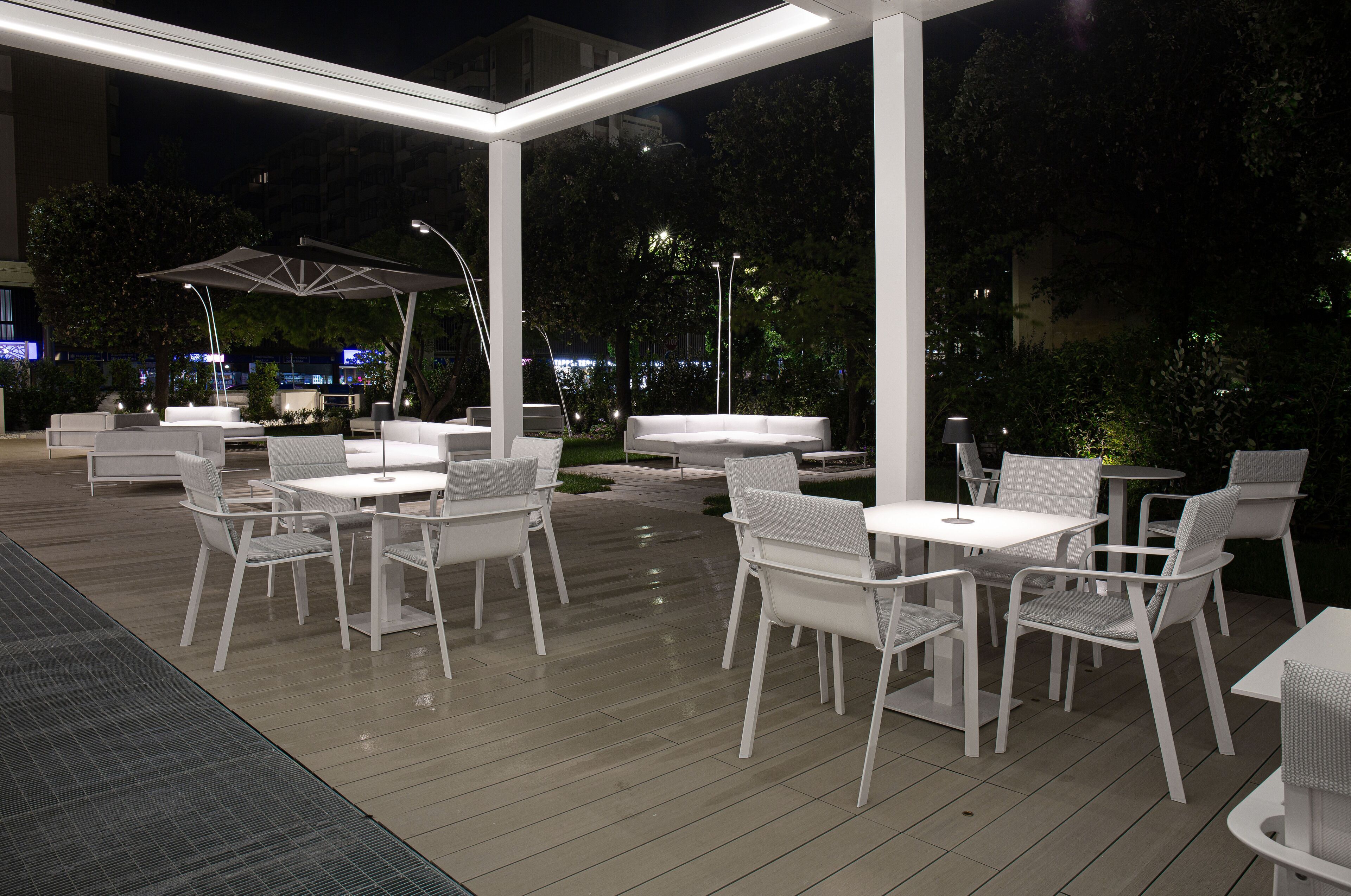 An outdoor patio area with white furniture and a covered seating area.
