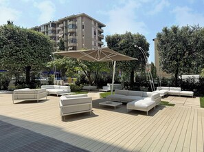 An outdoor seating area with modern furniture, a covered section, and a building in the background.