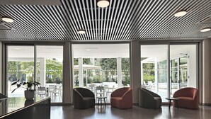 A modern lobby with a sleek ceiling design, large windows offering views of the outdoors, and contemporary seating arrangements. - Hotel Raffaello (Florence)
