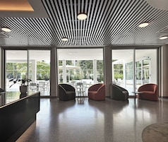 A modern lobby with a sleek ceiling design, large windows offering views of the outdoors, and contemporary seating arrangements.