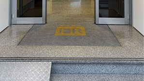 A hotel entrance with a glass door, a visible interior with tables and chairs, and a yellow tactile paving on the floor. - Hotel Raffaello (Florence)