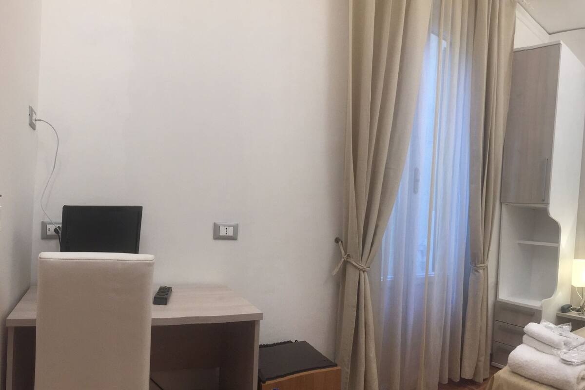 Une chambre d’hôtel équipée d’un bureau, d’une chaise, d’un lit et d’une télévision.