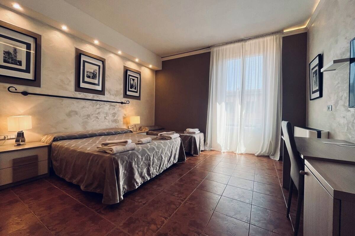 Une chambre d’hôtel avec un lit, des tables de chevet, un bureau et une chaise.