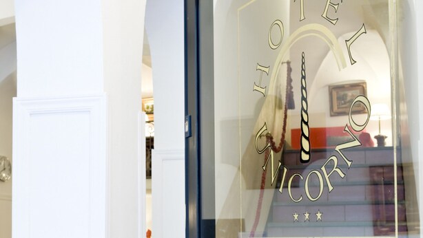 A hotel entrance with a glass door, a metal handle, and a sign reading "HOTEL MICORI" with three stars. - Hotel Unicorno (Florence)