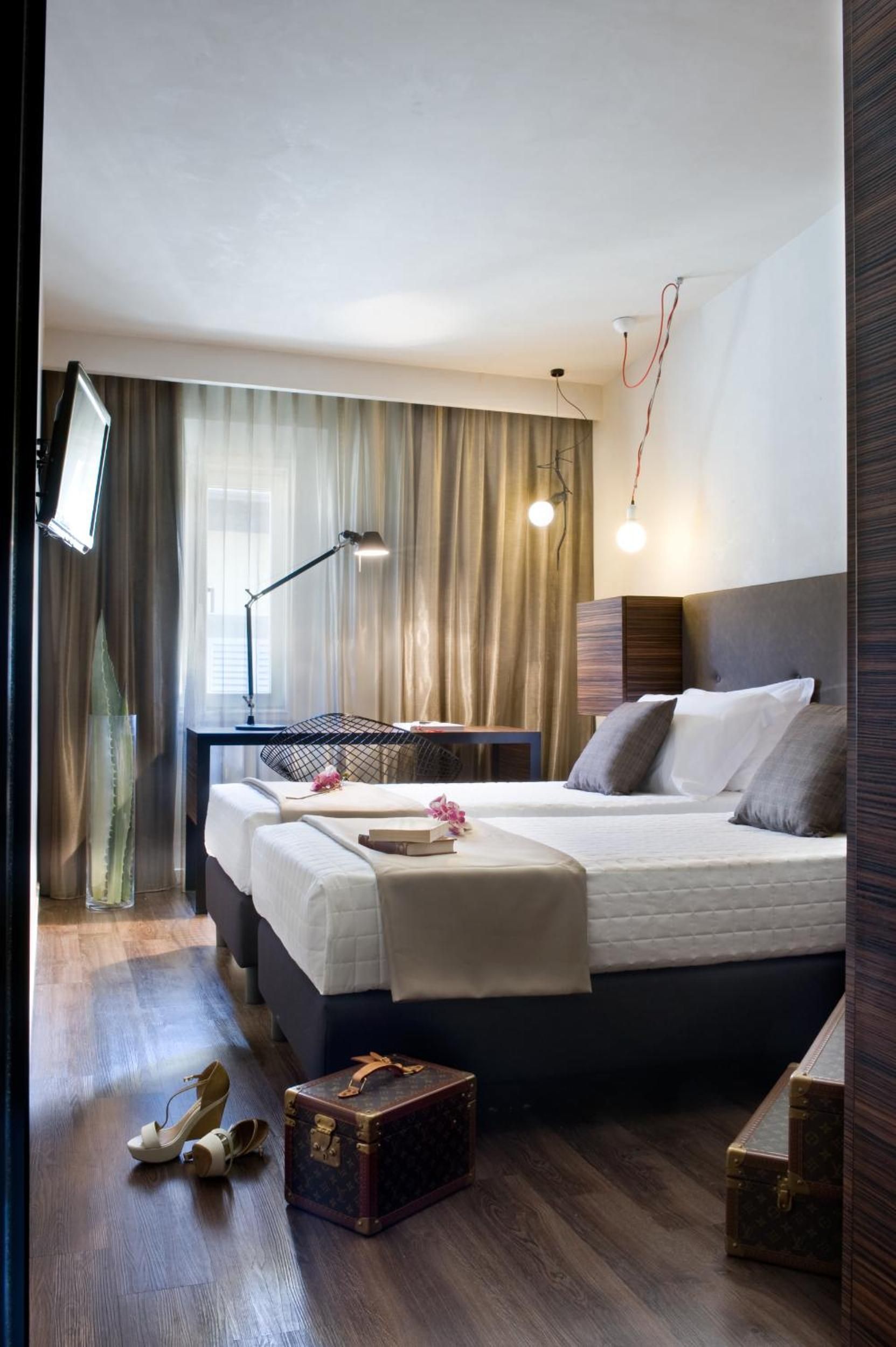 A modern bedroom with a large bed, bedside tables, a desk, and a television.