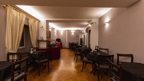 A dining area with wooden flooring, tables, and chairs. There is a red table with a cloth and a chandelier. - Hotel Unicorno (Florence)