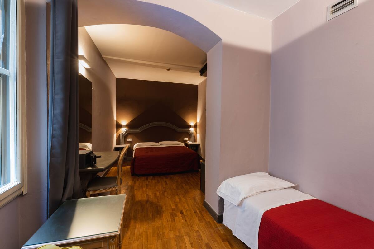 A compact hotel room with a single bed, a desk, and a chair.