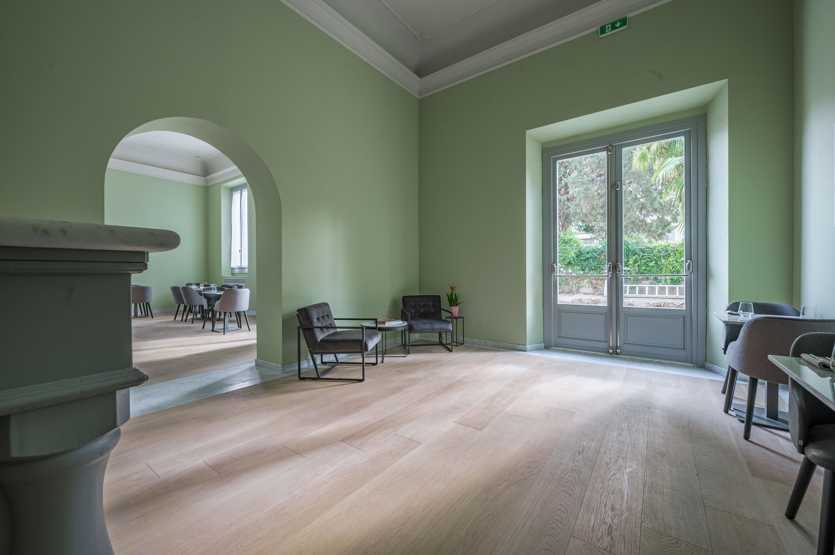 A spacious room with a large window, a fireplace, and a seating area with chairs and a table.