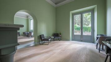 A spacious room with a large window, a fireplace, and a seating area with chairs and a table.