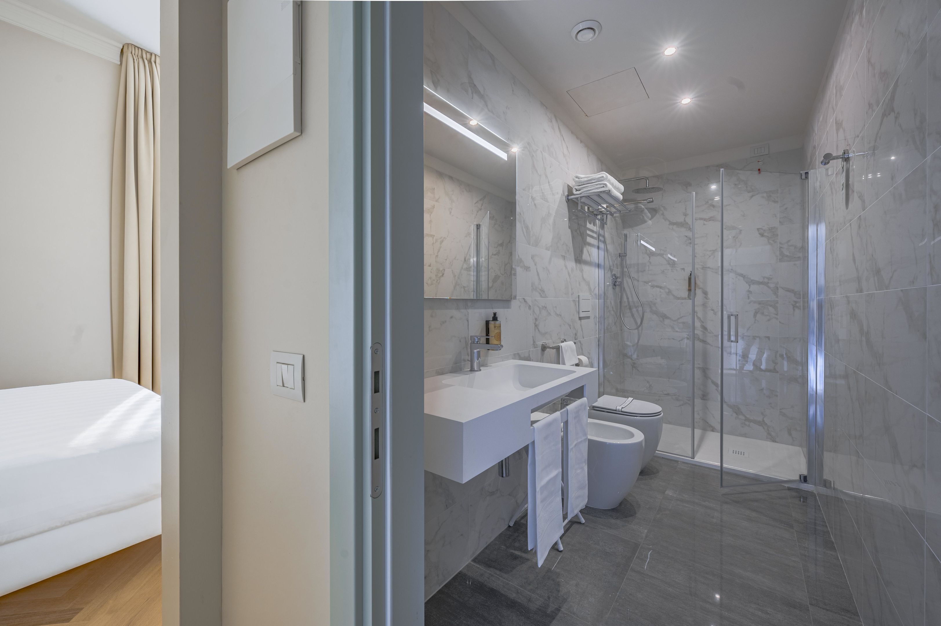 A modern bathroom with a glass shower enclosure, a white sink, and a toilet.