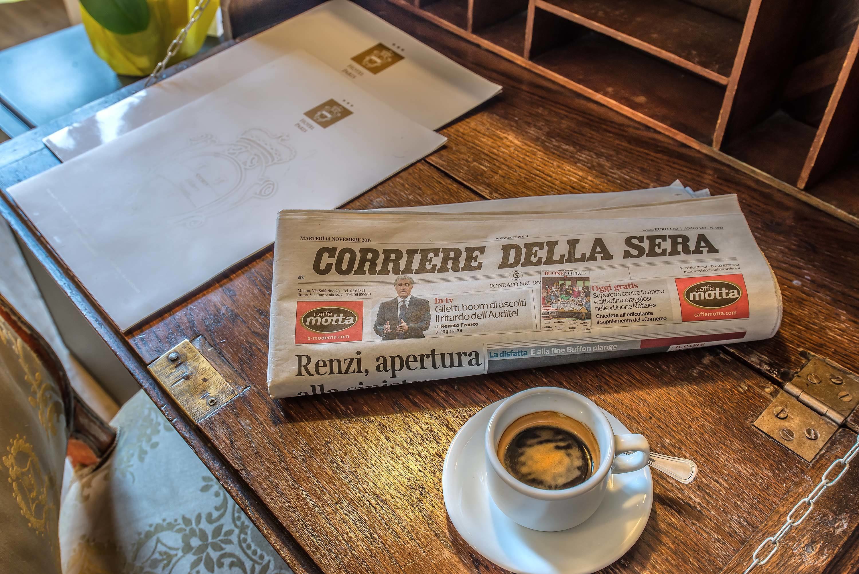A newspaper, a cup of coffee, and a wooden table.