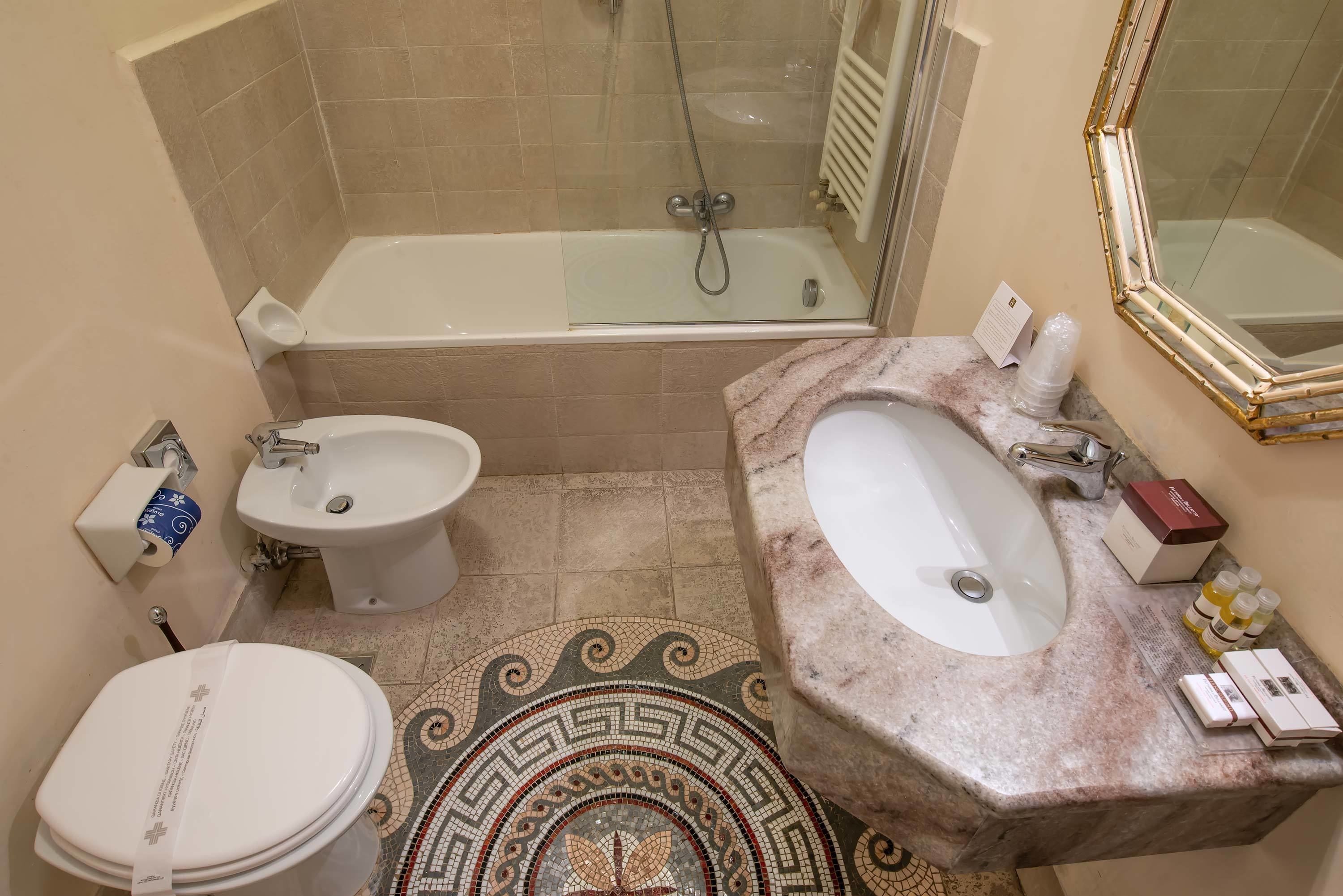 A bathroom with a bathtub, a sink, a toilet, and a bidet.
