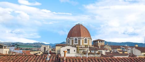 A domed building with a red roof and white walls, surrounded by terracotta-tiled rooftops.