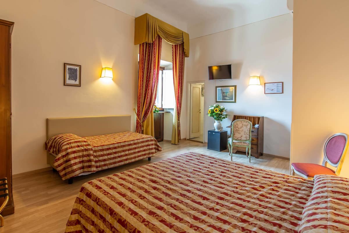 Une chambre d’hôtel avec deux lits, un bureau, une chaise et un téléviseur.