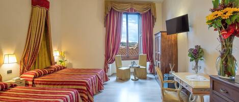 A hotel room with two beds, a desk, a chair, a TV, and a window with curtains.