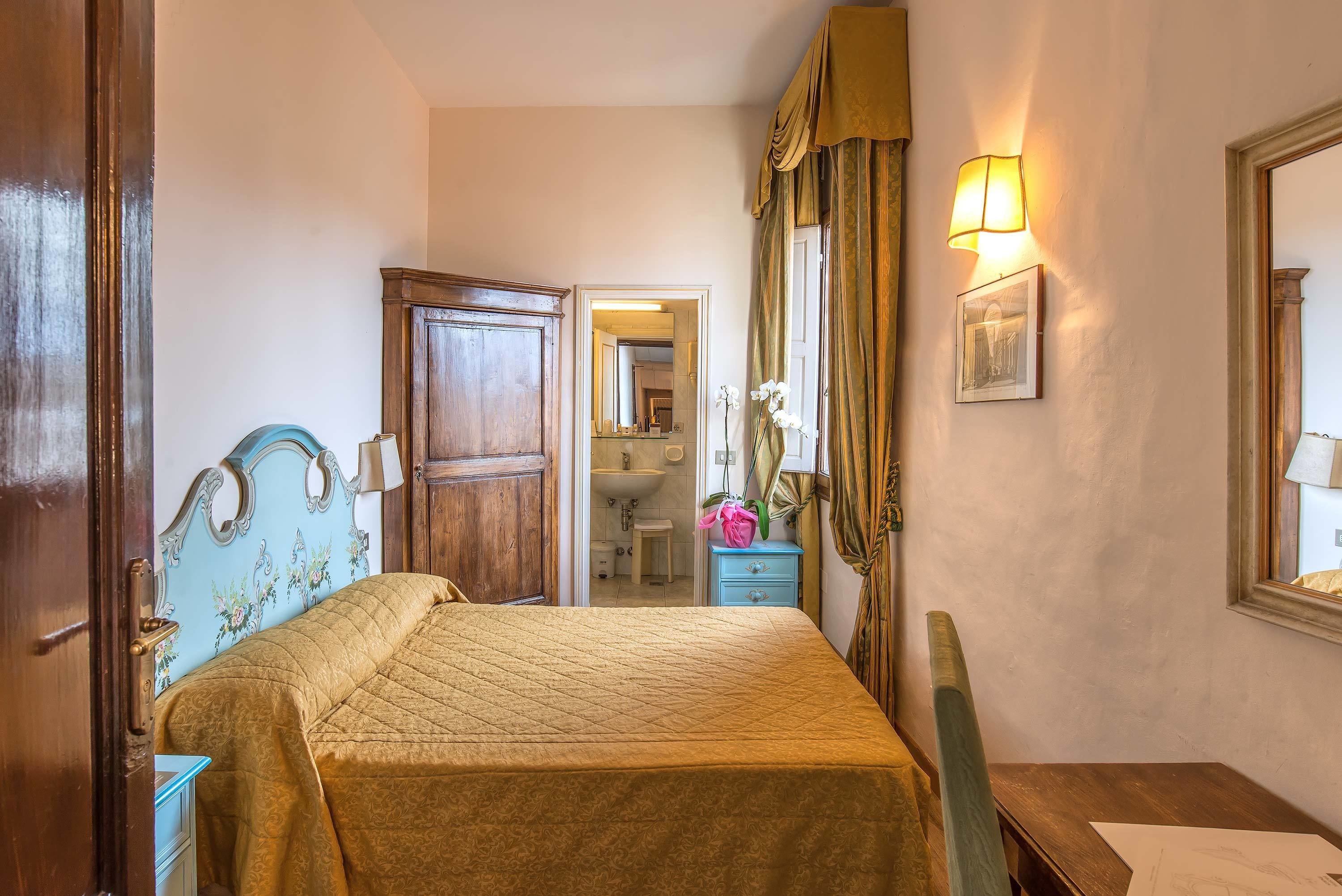 Ein Schlafzimmer mit einem Bett, einem Nachttisch, einer Kommode, einem Spiegel und einer Tür zu einem Badezimmer.