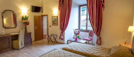 A hotel room with two beds, a desk, a chair, a TV, and a window with curtains.