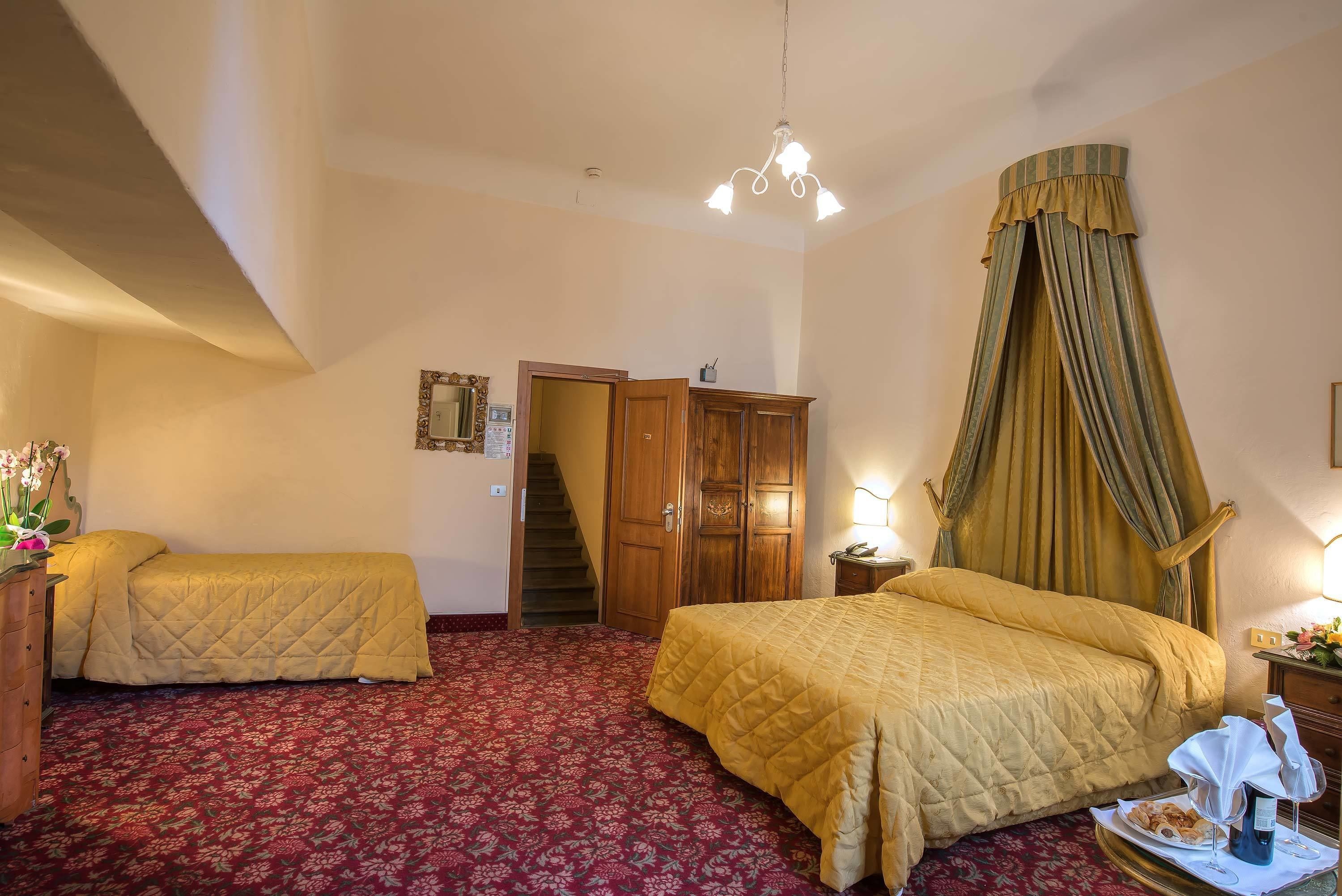 Habitación de hotel con dos camas, una escalera, un armario de madera y una cama con dosel.