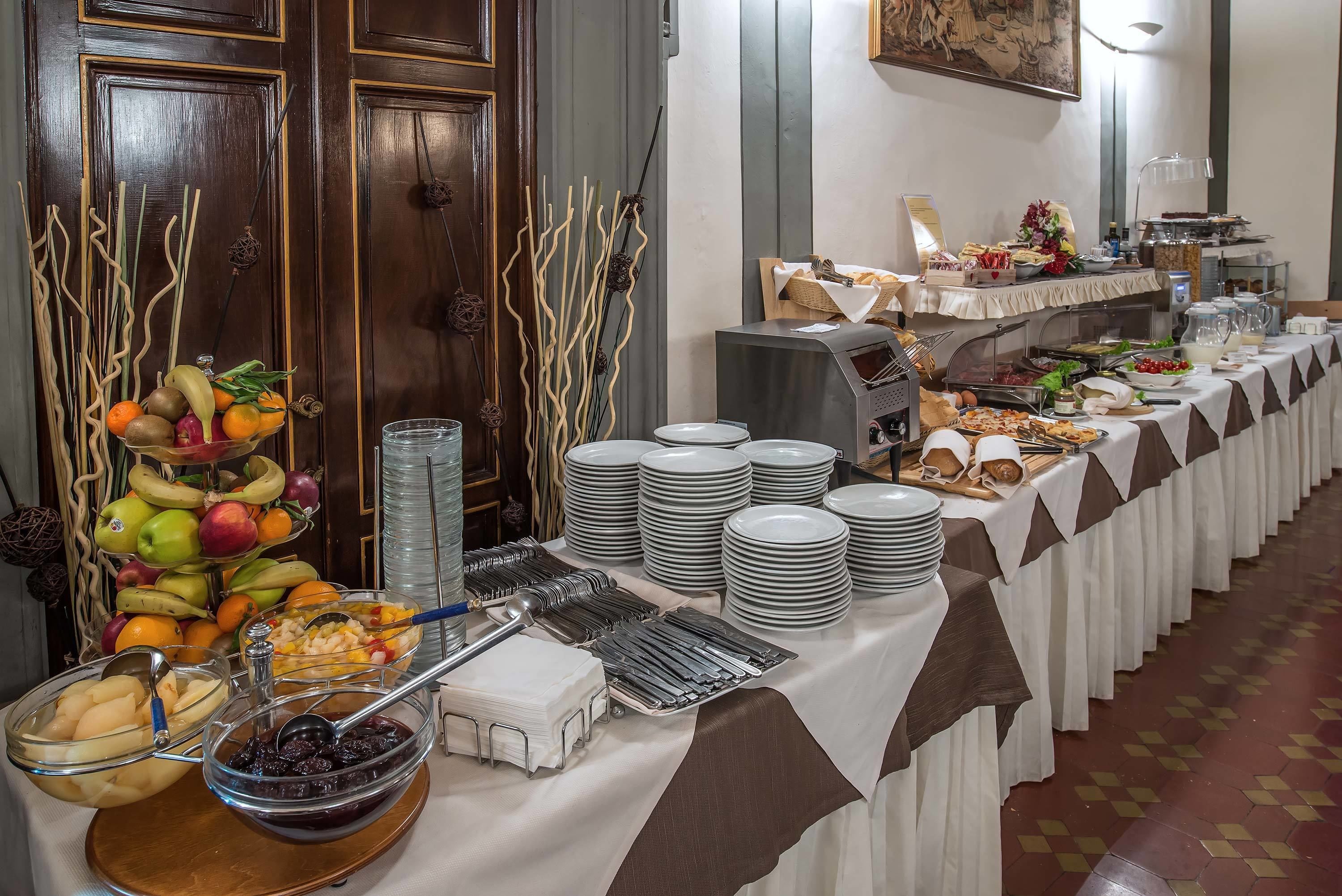 Una mesa de buffet con diversos alimentos, platos y utensilios.