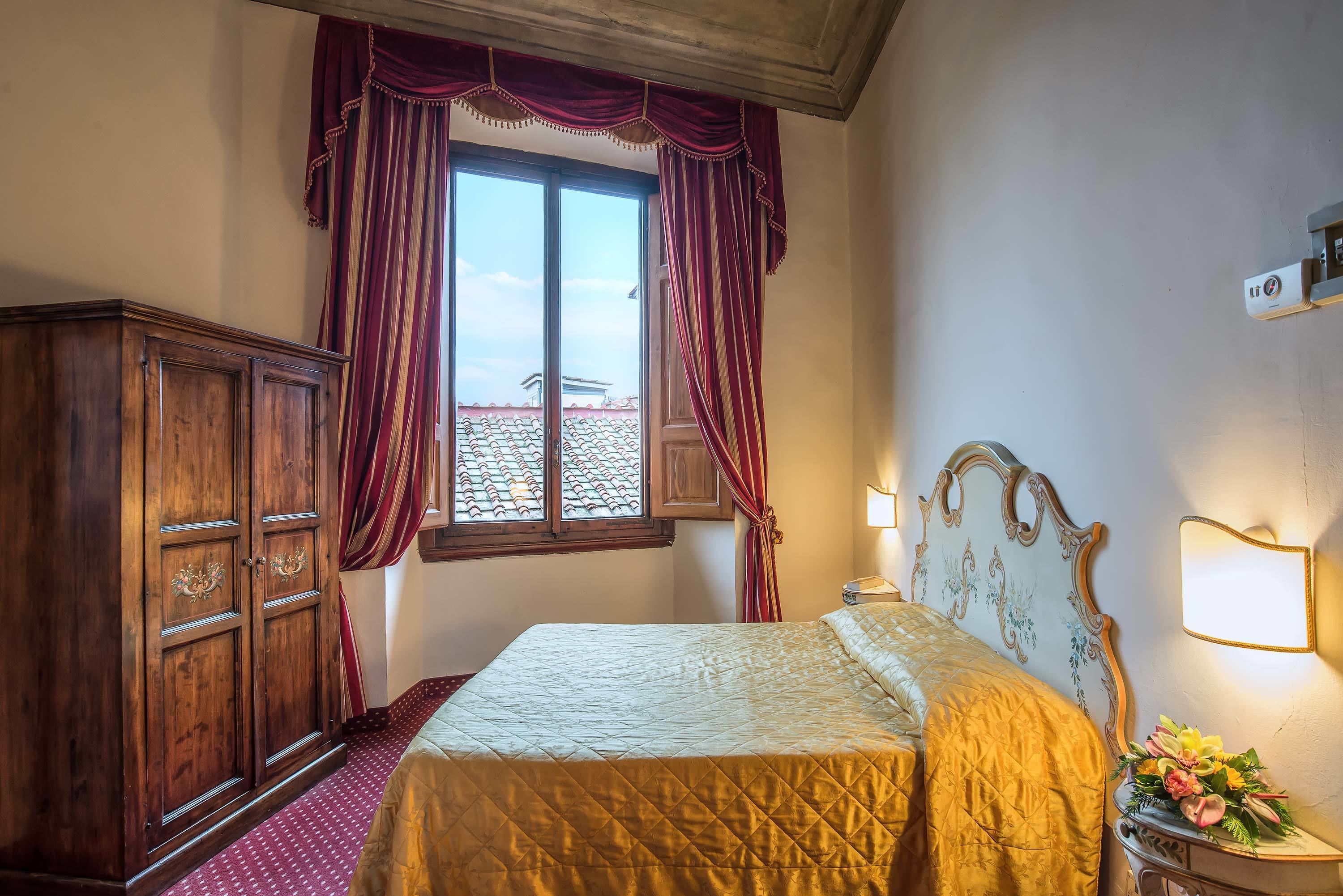 Un dormitorio con cama, armario de madera, cortinas y ventana con vistas.