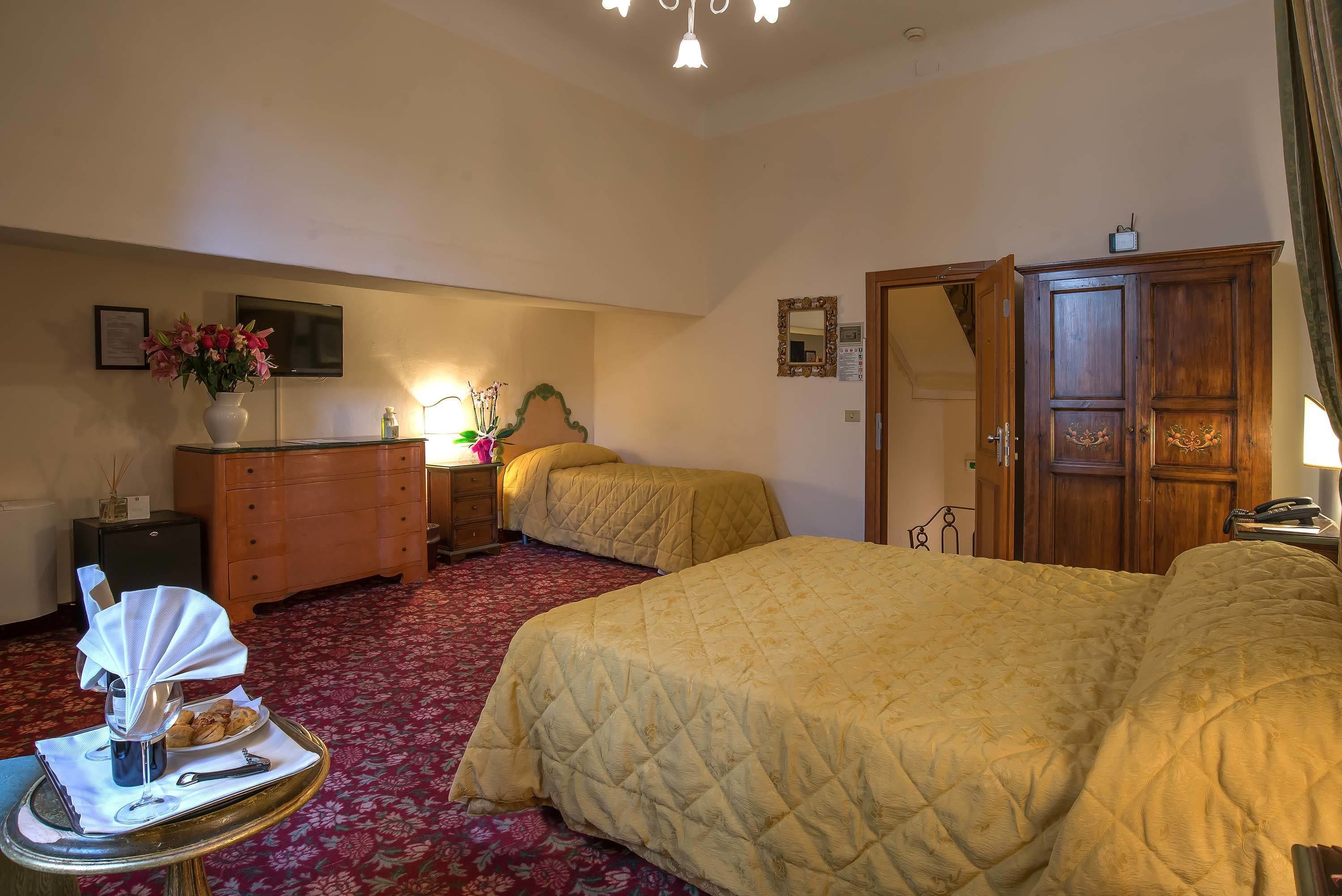 Une chambre d’hôtel avec deux lits, une commode, une télévision et un miroir.