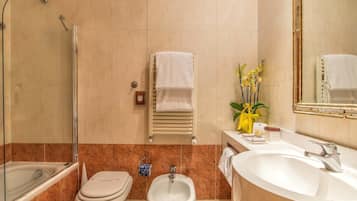 A bathroom with a glass-enclosed shower, a bidet, a sink, and a mirror.