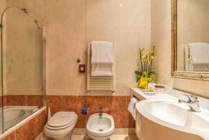 A bathroom with a glass-enclosed shower, a bidet, a sink, and a mirror.