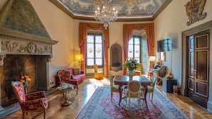 Une vaste pièce dotée d’une cheminée, d’un plafond richement décoré et d’un lustre.