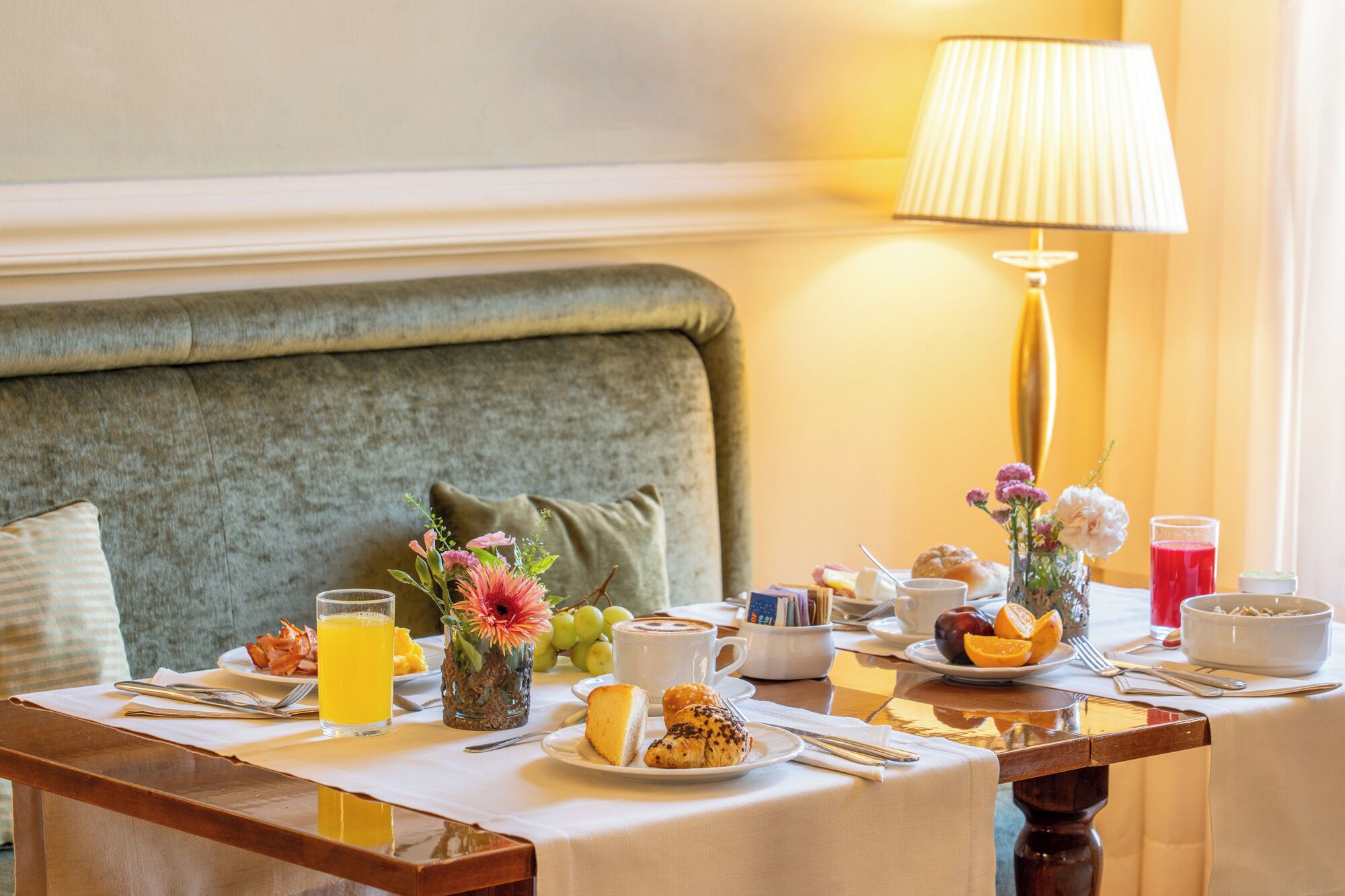 A breakfast table with a variety of food items, including pastries, fruits, and a glass of orange juice.