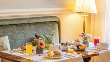 A breakfast table with a variety of food items, including pastries, fruits, and a glass of orange juice.