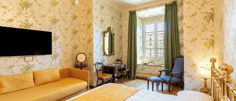 A hotel room with a bed, a sofa, a desk, and a chair.
